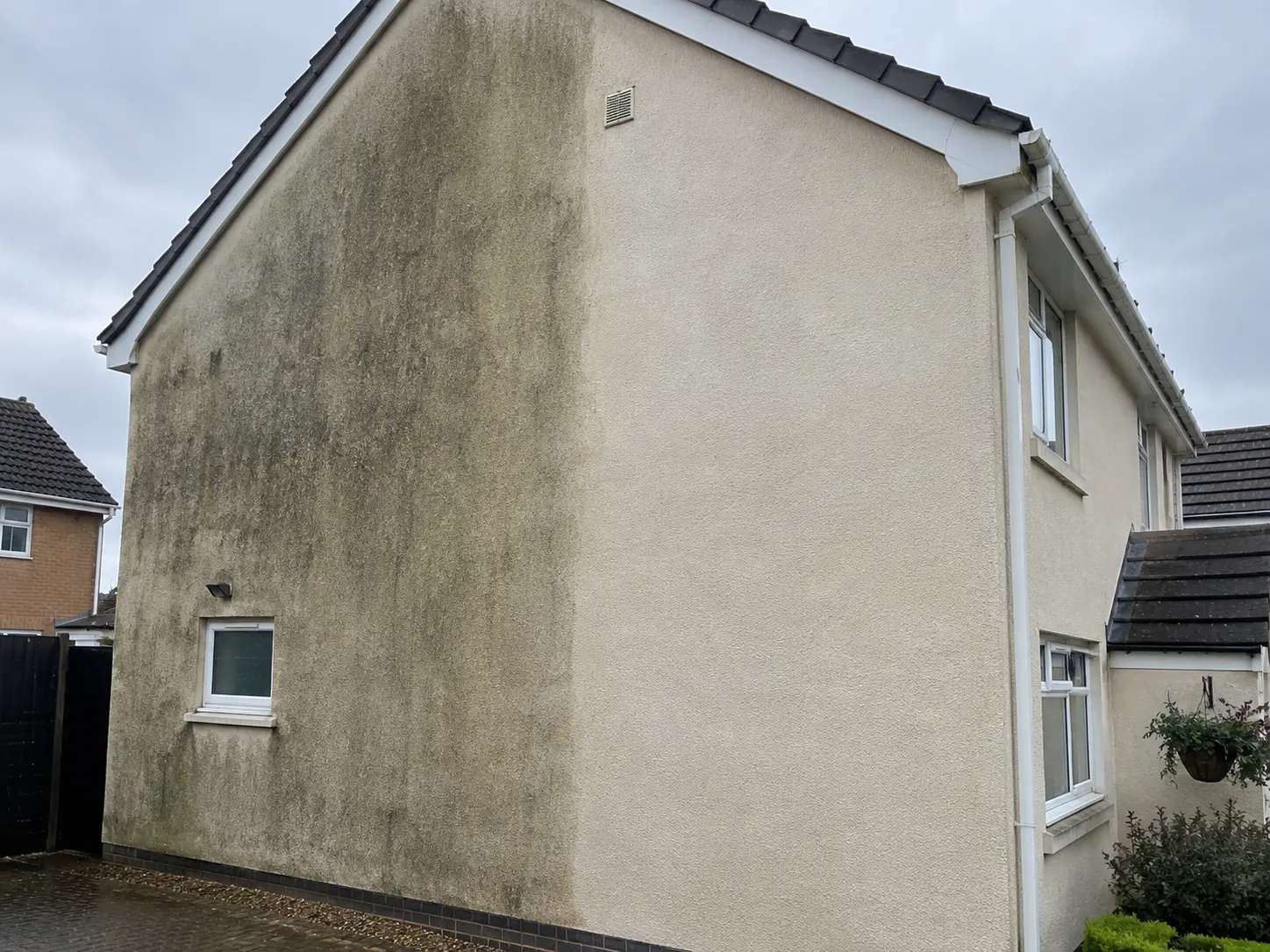 Rendered gable wall with the algae staining cleaned off the right half